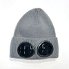 A gray knit windproof hat with round black goggles attached to the front.