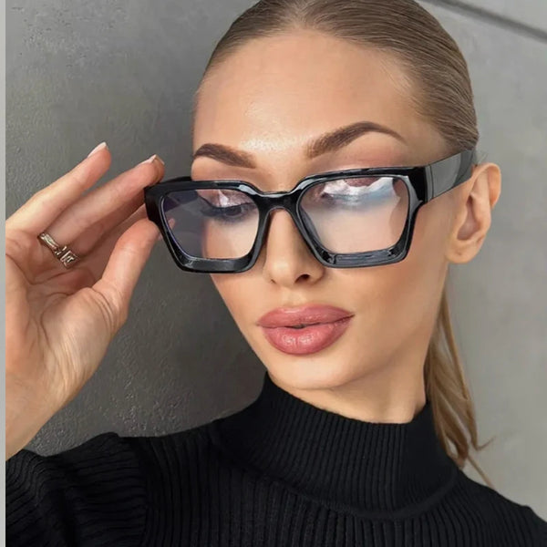 A woman wearing black vintage square eyeglasses with clear lenses and a black turtleneck sweater.
