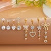 A set of gold dangle curved belly piercing jewelry featuring heart and flower designs on a beige background.