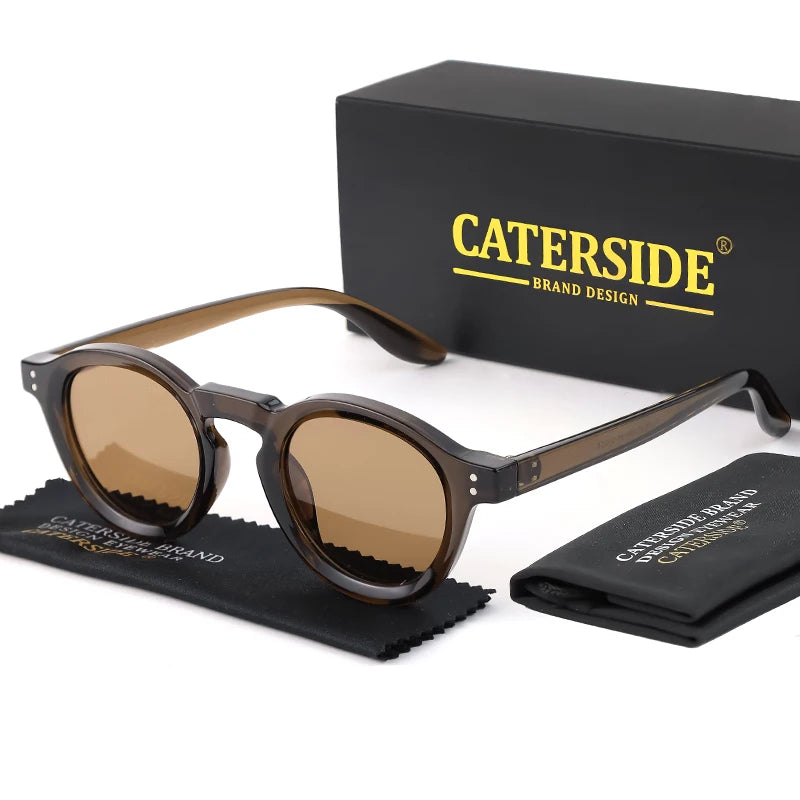 نظارات شمسية من جلد السلحفاة البني موضوعة على قماش أسود بجوار صندوق أسود يحمل علامة CATERSIDE BRAND DESIGN.