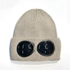 A beige knit windproof hat with round black goggles attached to the front