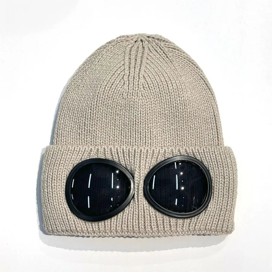 A beige knit windproof hat with round black goggles attached to the front