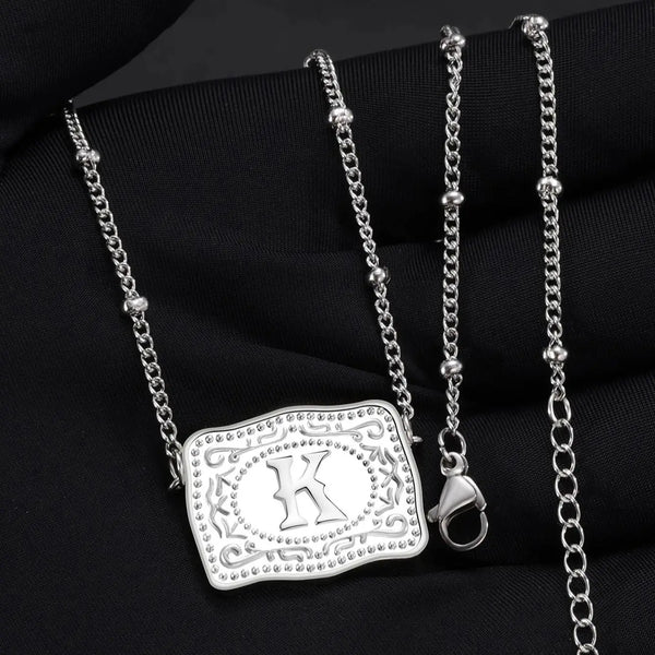 Pendentif initial argent avec pendentif cœur et chaîne délicate, présenté sur tissu noir.