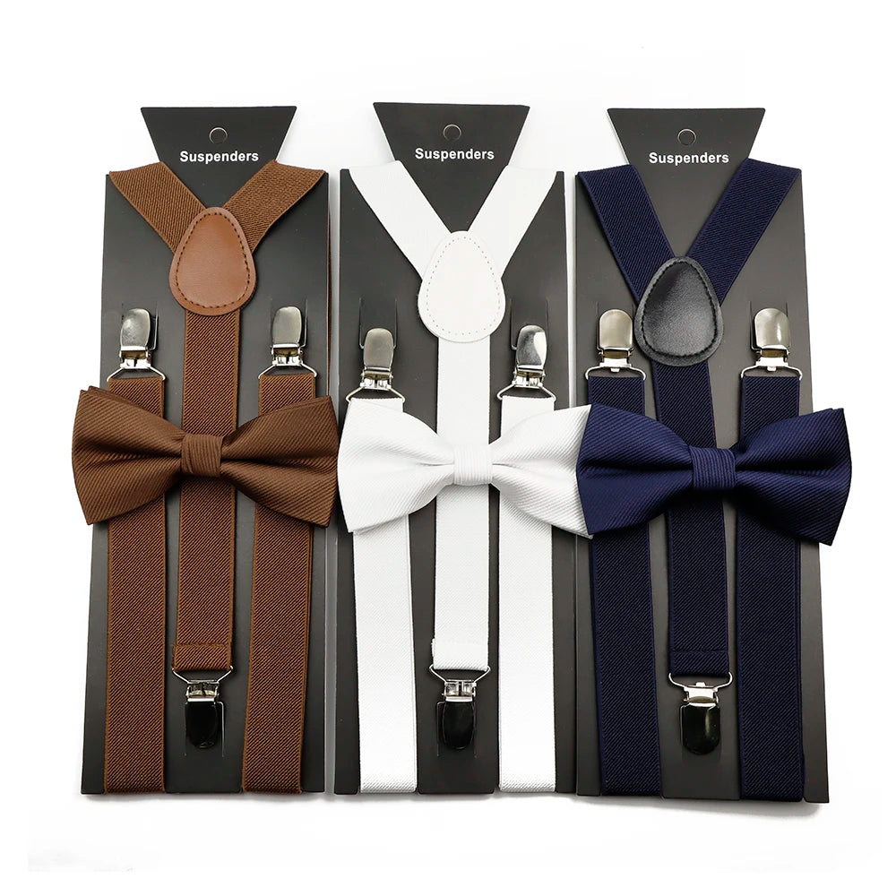 A set of adjustable polyester suspenders and bow ties in brown, white, and navy colors displayed in packaging.