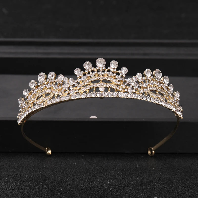 Gold-toned crystal rhinestone bridal tiara headpiece displayed on a dark surface.