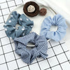 A flat lay of three fabric scrunchie headbands in blue and white patterns, along with two dark brown knitted balls.