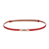 A skinny leather belt with a rose gold buckle and red stitching.