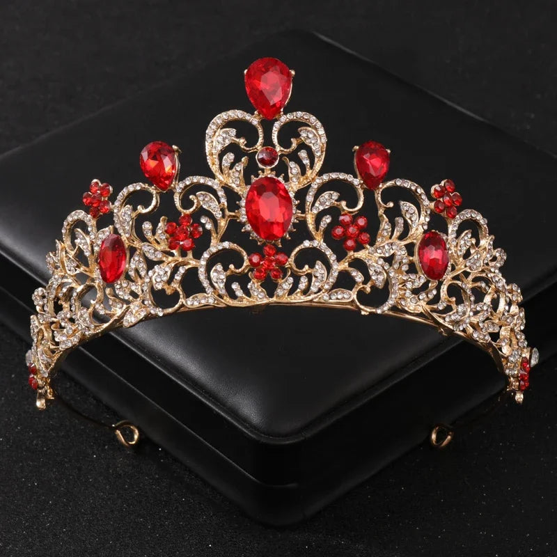 Tiare et couronne en strass de cristal or et gemmes rouges, présentées dans une boîte noire.