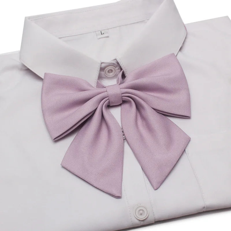 A white dress shirt with a lavender butterfly ribbon tie set folded and displayed.