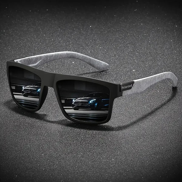 A pair of black polarized sunglasses with a silver strap resting on a dark, speckled surface.