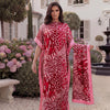 A woman models a long red and pink leopard zebra print kaftan outdoors near a white building.