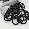A pile of black elastic hair bands is shown in a clear plastic bag.