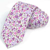 Une pile de cravates en coton à imprimé floral élégantes dans des tons de violet et de rose.