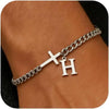 A close-up of a personalized stainless steel cross Cuban chain bracelet worn on a wrist.