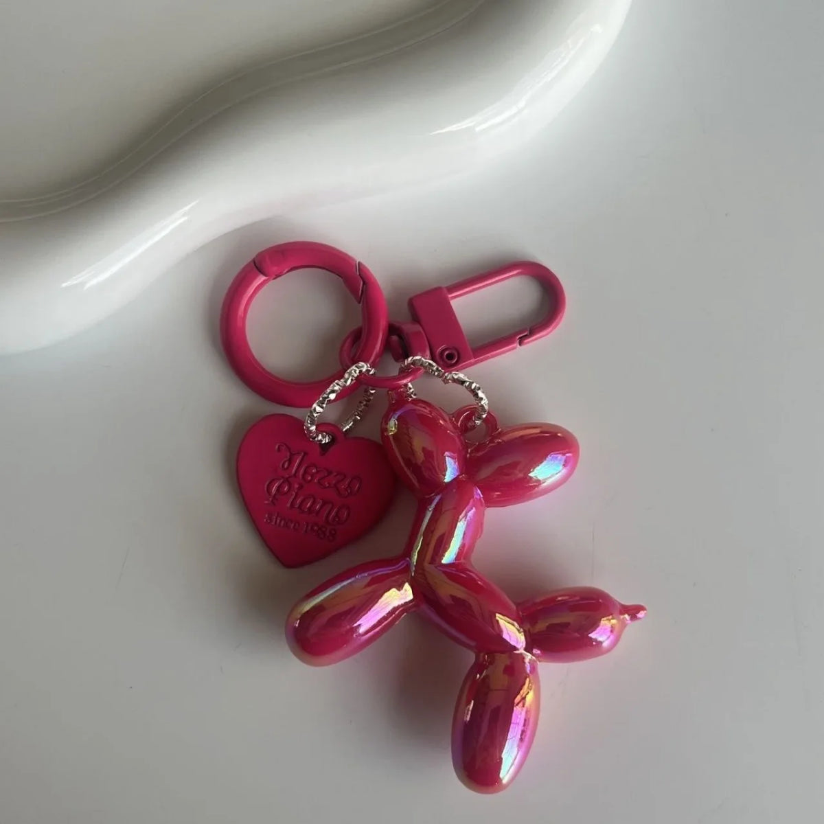 A pink jelly cartoon dog keychain with a heart-shaped charm and a pink loop.