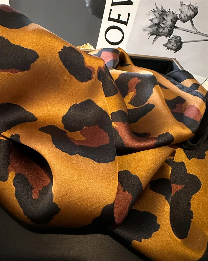 Nahaufnahme eines luxuriösen Leopardenmuster-Seidenschals in Gold-, Braun- und Schwarztönen, elegant drapiert.