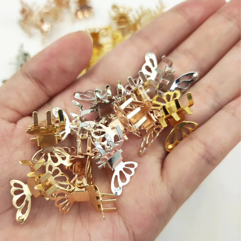 A hand holds a set of ten mini hollow butterfly metal hair clips in various gold and silver tones.