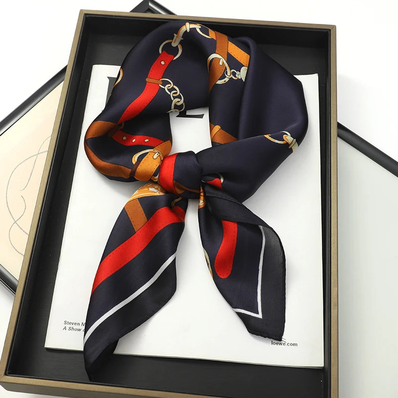 A navy blue silk scarf tied in a bow with gold and red accents displayed in a wooden frame.