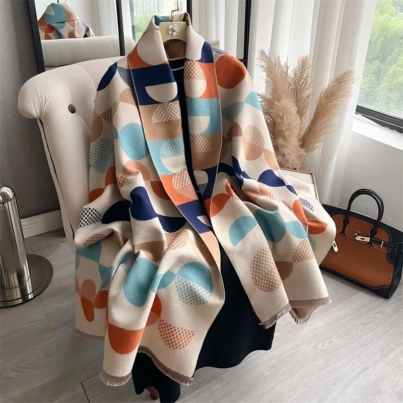 A luxury plaid cashmere feel scarf and shawl wrap in shades of orange, blue, cream, and navy draped over a white chair.