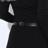 Primer plano de un cinturón de cadena de cuero negro usado alrededor de la cintura de una mujer con una blusa negra de manga 