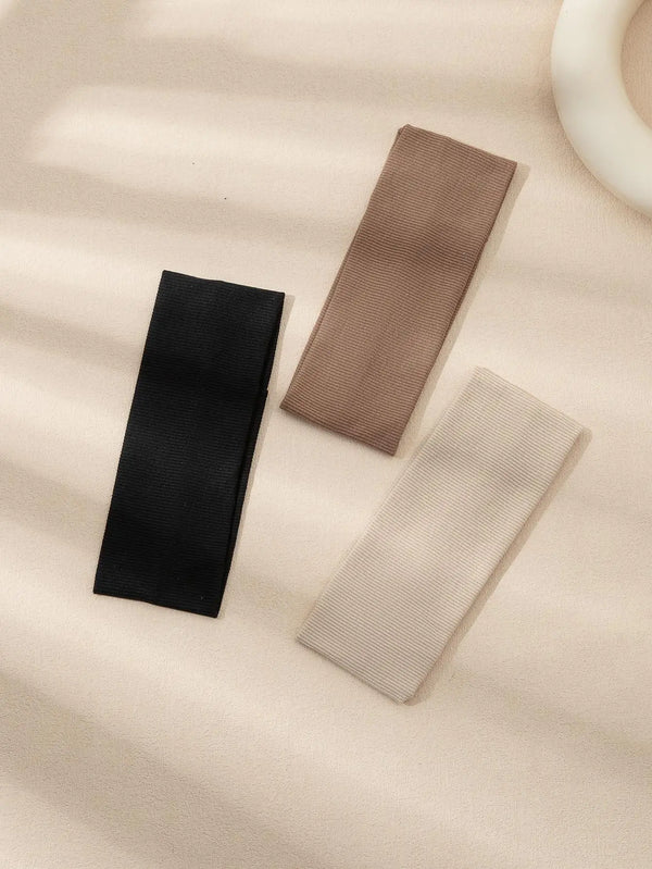 Drei farbige Mode-Haarbänder in Schwarz, Taupe und Beige auf hellem Hintergrund.
