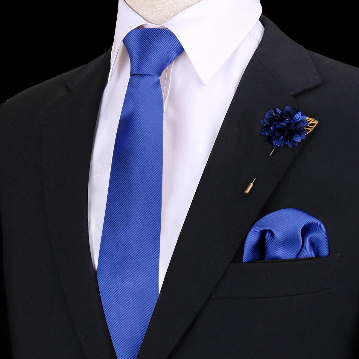 Chaqueta de traje oscura con camisa blanca, corbata de seda azul y pañuelo de bolsillo floral azul.
