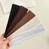 A hand holds several solid colored fabric headbands, including black, brown, beige, and white.