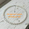 Weißer Perlen-Choker und Armband-Set mit silberner Kettendetail auf hellem Holz.