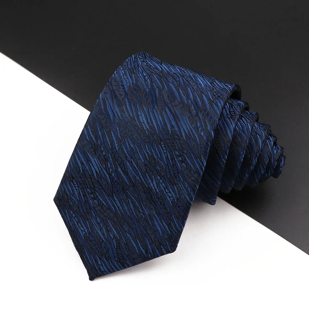 Dunkelblaue Luxus-Krawatte für Herren mit strukturiertem Blumen-Paisley-Muster, gefaltet auf weißem Untergrund.