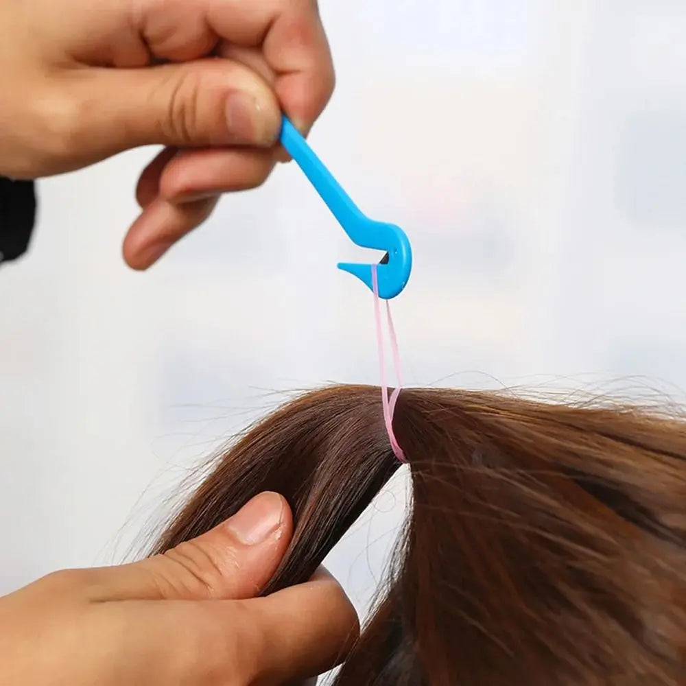 A hand is using a blue tool to remove an elastic from a strand of brown hair.