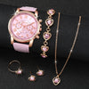 A pink quartz wristwatch with gold accents and a matching gold chain necklace are displayed on a dark surface.
