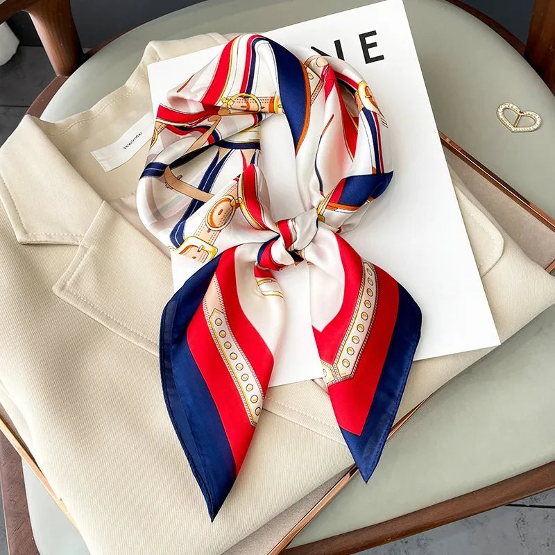 A luxury silk scarf featuring red, white, and blue stripes tied in a bow, displayed on a white card.