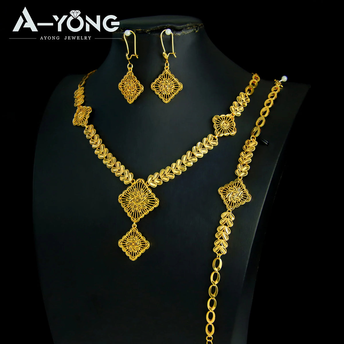 A luxury gold plated bridal jewelry set featuring earrings and a necklace displayed on a black mannequin.
