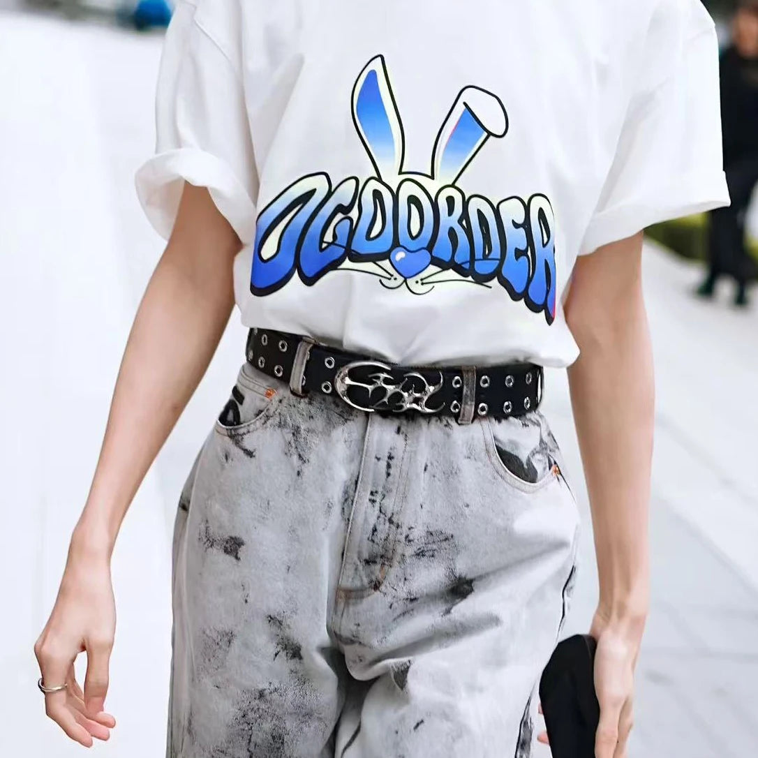 A person wearing a white t-shirt with blue text and gray distressed jeans and a black belt.