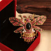Broche ton or avec motif abeille baroque et insecte, pierres roses et noires dans une boîte de velours rouge.