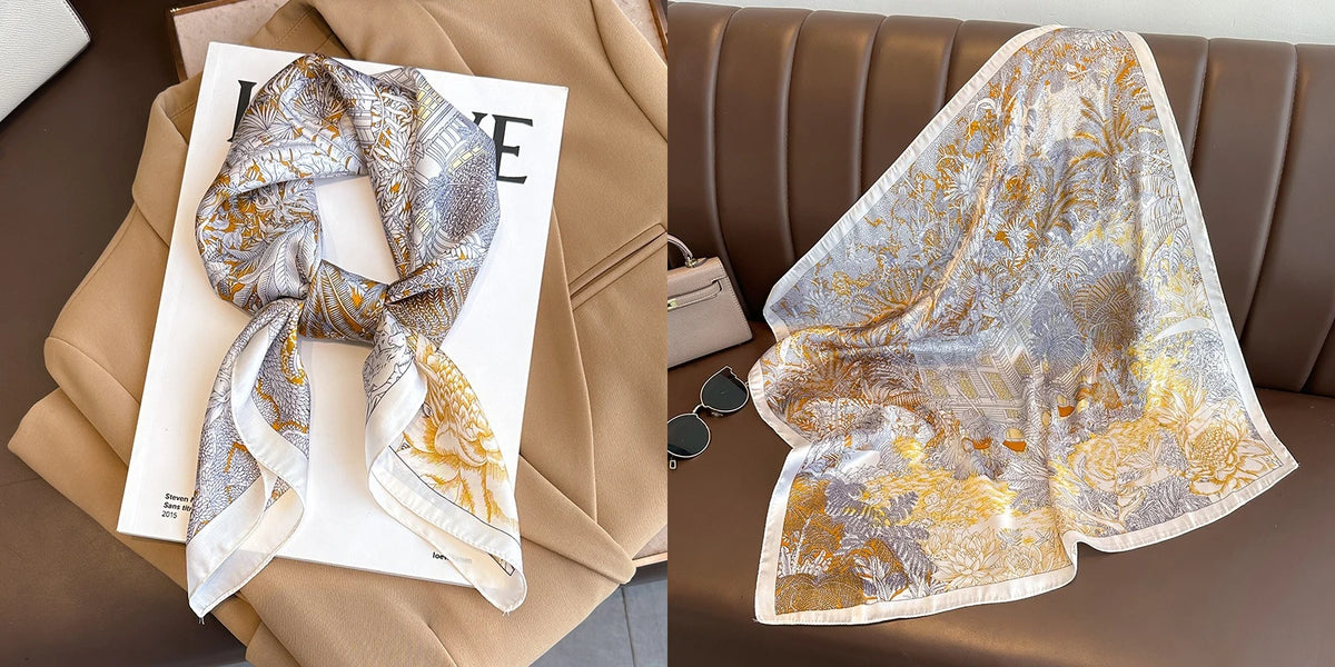 A light gold and silver floral print silk scarf draped on a beige jacket next to a brown leather sofa.