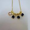 Goldener Anhänger mit rosa und blauen Edelsteinen auf goldener Kette