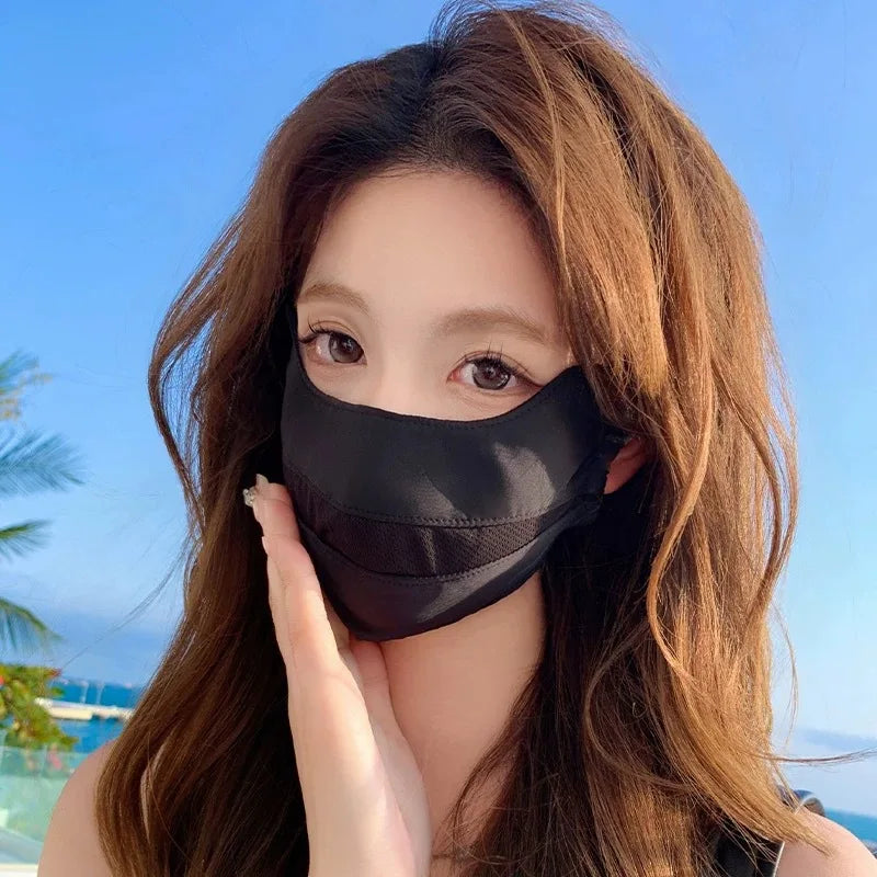 A woman wearing a black breathable ice silk UV protection face mask against a bright blue sky background.