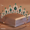 Elegant crystal baroque bridal tiara featuring green gemstones and silver-toned metal set against a neutral background.