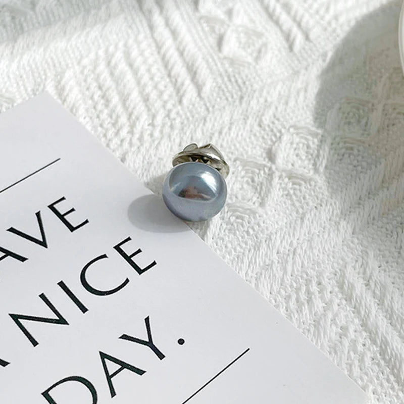 Silver pearl button set resting on a white card against a textured white background.
