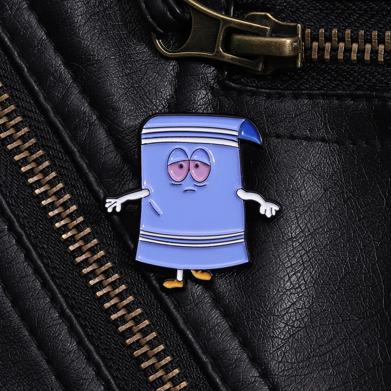A blue cartoon towel enamel pin with a surprised expression is attached to a black leather jacket.