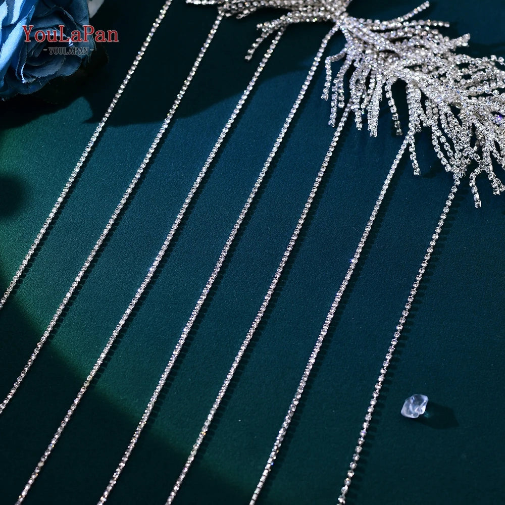 Tasseles de cadena para taladro plateados y una diadema nupcial, exhibidos sobre una superficie verde oscura.