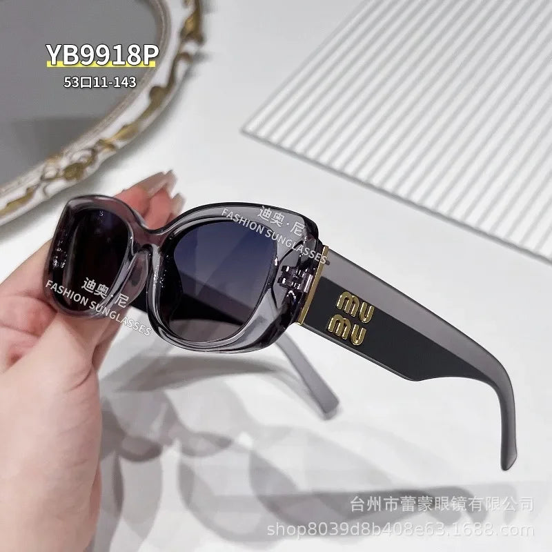 A pair of black polarized fashion sunglasses with gold accents resting on a hand.