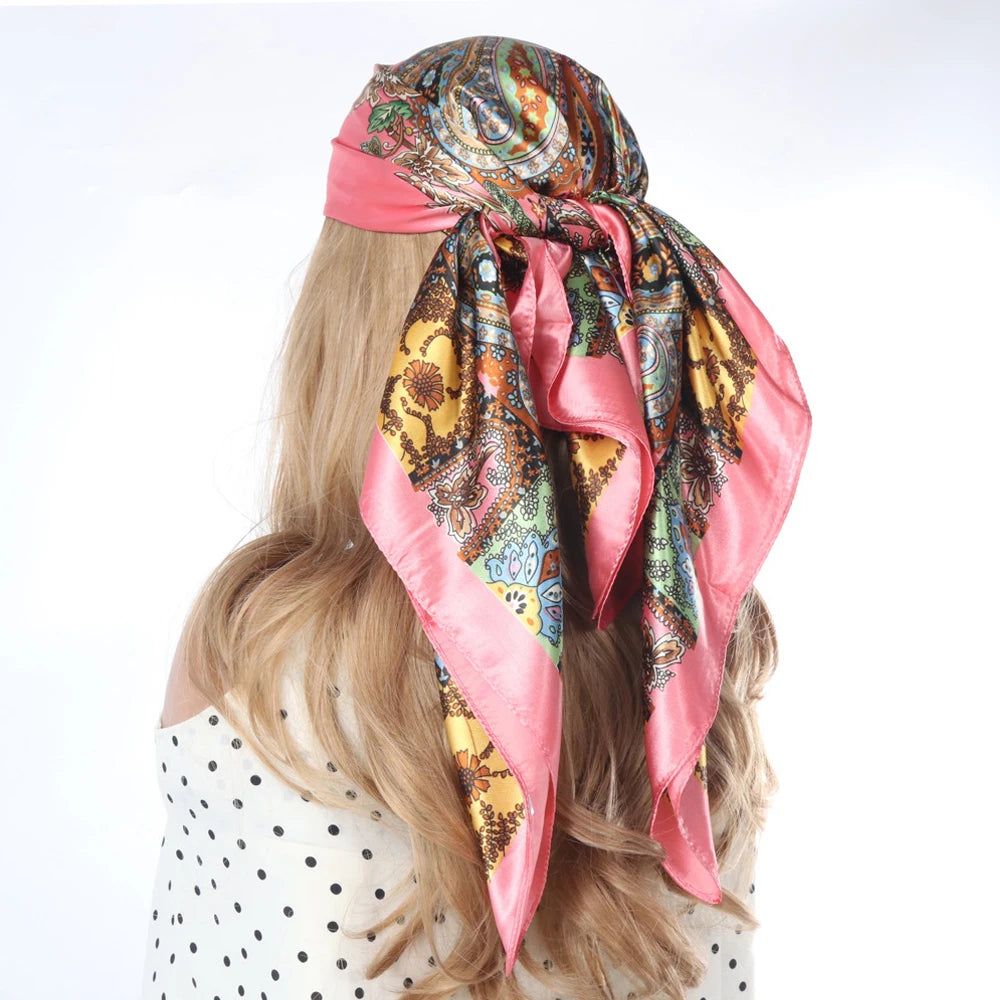 Eine Frau mit langen blonden Haaren trägt einen rosa gemusterten Boho-Seiderschal als Kopftuch.