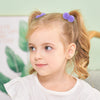 A young girl with blonde hair is shown wearing purple plush elastic hair bands.