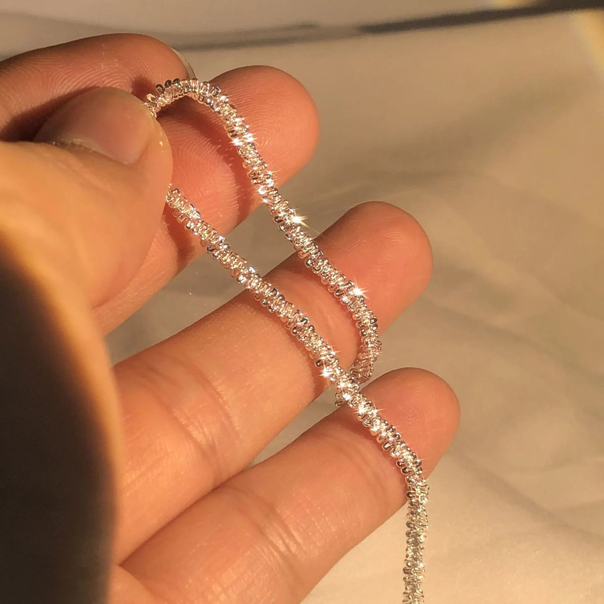 Eine Hand hält eine Sterlingsilber-Halskette für die Schlüsselbein mit 2mm funkelnden Elementen.