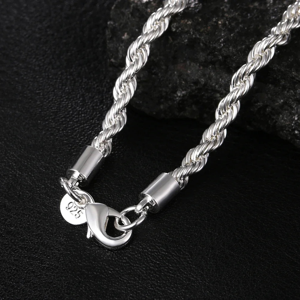 A silver twisted rope necklace and bracelet set displayed on a dark surface.