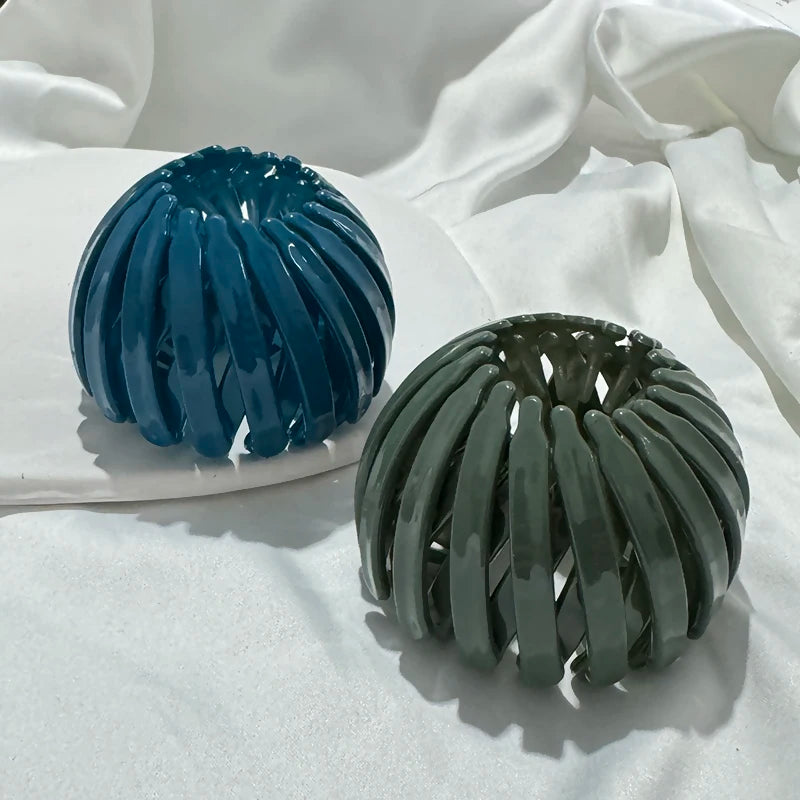 A pair of elegant horsetail hair clips in blue and green are displayed on a white surface.