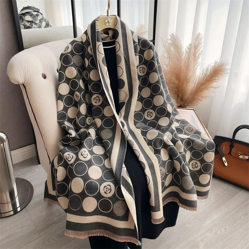 A beige and black patterned cashmere scarf draped over a hanger in a bright, modern room.