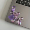 A purple resin animal dog keychain with a silver chain and purple clasp resting on a laptop.